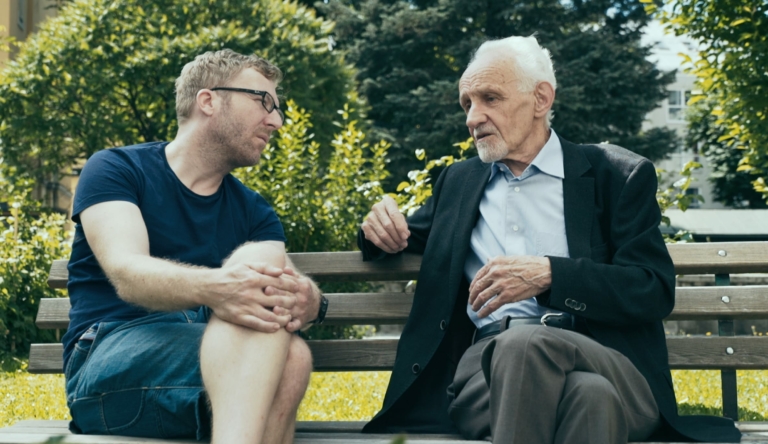 Marc Brugger führt auf einer Gartenbank ein Interview mit einem Pater der Jesuiten.